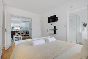 a white bedroom with a bed with two towels on it at Quality Apartments Close to Tube in Hendon