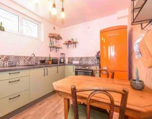 a kitchen with a wooden table and an orange refrigerator at Les Valéricaines Appartement Vieille Ville Saint Valery sur Somme in Saint-Valery-sur-Somme