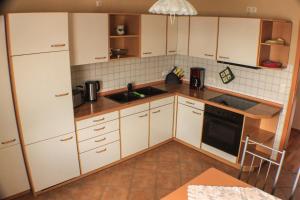 una cocina con armarios blancos y fregadero en Ferienwohnung Rochlitzer Berg Blick, 