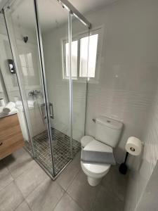 La salle de bains blanche est pourvue d'une douche et de toilettes. dans l'établissement Apartamento Entre dos mares, à Tarifa