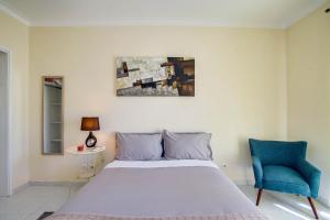 a bedroom with a large bed and a blue chair at Peniche Sun & Surf Apartment in Peniche