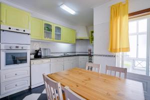 a kitchen with a wooden table and yellow cabinets at Peniche Sun & Surf Apartment in Peniche