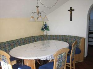 a dining room table with chairs and a cross on the wall at Apart Sonneck in Arzl im Pitztal