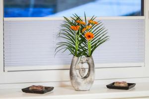 wazon z pomarańczowymi kwiatami siedzący przed oknem w obiekcie Appartement Gimpl w mieście Fusch an der Großglocknerstraße