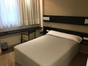 a bedroom with a white bed and a chair at Blu Hotel Pamplona in Imárcoain
