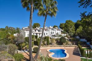 un grand bâtiment blanc avec des palmiers et une piscine dans l'établissement Casa Basta, à Moraira