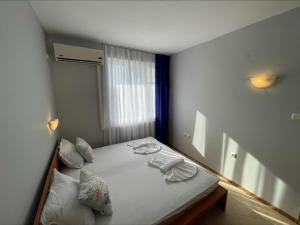 una piccola camera da letto con un letto con lenzuola e cuscini bianchi di Sunny Beach Hills - Menada Apartments a Sunny Beach