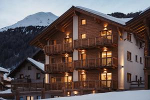 una casa de madera con terraza y montañas al fondo en Mountain Lodge - Livigno en Livigno