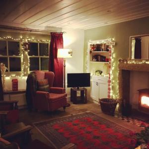 uma sala de estar com lareira e luzes de Natal em Sanctuary Cottage at Blacko em Barrowford