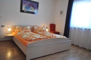 1 dormitorio con cama con sábanas de color naranja y ventana en Ferienwohnung Wilhelm en Sautens