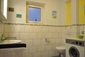 baño con lavabo y aseo y ventana en Ferienwohnung Wilhelm en Sautens