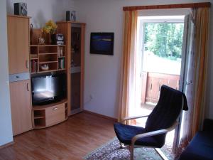 a living room with a chair and a television at Ferienwohnung Jirkal in Sankt Martin bei Lofer +3 photos