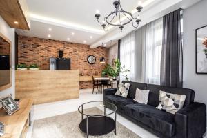 a living room with a black couch and a brick wall at RentPlanet - Apartament Wieliczka in Wieliczka +16 photos