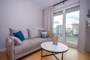 ein Wohnzimmer mit einem Sofa und einem Tisch in der Unterkunft InPoint Tauron Arena Apartment with Parking - Lema 17 in Krakau
