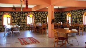 a dining room with tables and chairs and windows at TARiH OTEL NEMRUT DAGI in Karadut