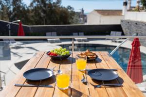 a wooden table with a bowl of fruit and glasses of orange juice at Malpique Guest House & Jacuzzi in Albufeira