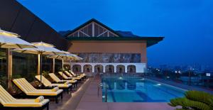 una piscina de hotel con sillas y sombrillas por la noche en Radisson Jaipur City Center, en Jaipur