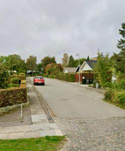 un coche rojo está conduciendo por una calle en Cosy apartment with private terrace en Vallensbæk