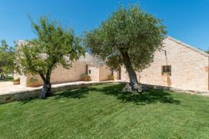 カステッラーナ・グロッテにあるTrulli Oasi Fiorita - Exclusive Apulian Holidaysの建物前の芝生の木々