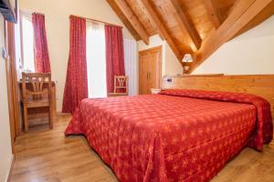a bedroom with a bed with a red bedspread at Locanda Alla Stella in Roana