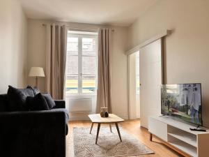 a living room with a couch and a tv at Beautiful, modern 1-bed apartment, 5 mins RER A in Saint-Germain-en-Laye