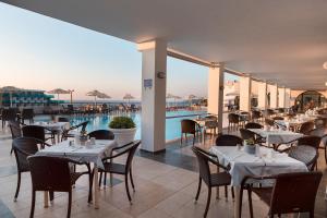 a restaurant with tables and chairs and a swimming pool at Calypso Palace in Faliraki