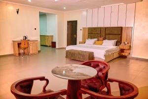 贝宁城Bosanic Hotel的一间卧室，配有一张床、一张桌子和几把椅子