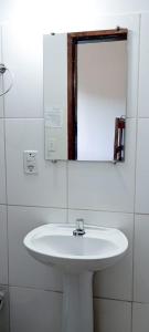 y baño con lavabo blanco y espejo. en HOTEL JP, en Delfinópolis