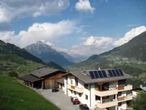 Bauernhof Huber في فينس: منزل به لوحات شمسية على السطح مع جبال
