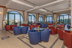 a restaurant with red and blue chairs and windows at Calypso Palace in Faliraki