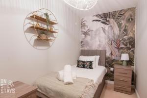 a bedroom with a bed and a shelf with plants at OnSiteStays 2BR, Parking, Wifi, Shops and Restaurants Close in Hatfield