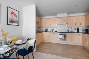 una cocina con armarios de madera y una mesa con sillas. en OnSiteStays 2BR, Parking, Wifi, Shops and Restaurants Close en Hatfield