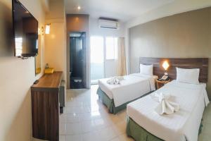 a hotel room with two beds and a television at Eastiny Inn Hotel in Pattaya