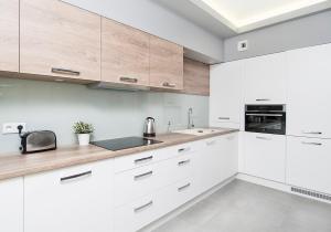 una cocina blanca con armarios blancos y fregadero en Landmark Apartments, en Cracovia