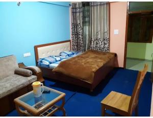 a bedroom with a bed and a couch and a table at HOTEL HIMGIRI, Shri Badrinath in Badrinath