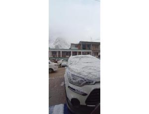 a snow covered car parked in a parking lot at HOTEL HIMGIRI, Shri Badrinath in Badrinath