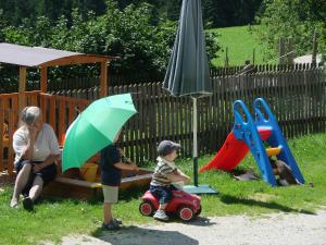 una mujer y dos niños jugando en un patio de juegos en Pircherhof - Urlaub und Erholung im Troadkost'n, en Sankt Kathrein am Hauenstein