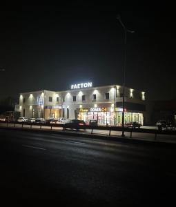 a building with a neon sign on the side of a street at Faeton in Almaty