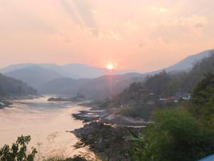 - une vue sur une rivière au coucher du soleil avec des bateaux dans l'établissement Dorm Riverside, à Pakbeng