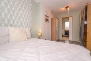 ein Schlafzimmer mit einem großen weißen Bett in einem Zimmer in der Unterkunft Les Valéricaines - Bel appartement - vue sur les toits de St Valéry in Saint-Valery-sur-Somme