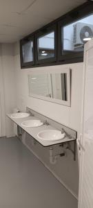 a bathroom with three sinks and a mirror at Albergue Santiago Apostol in Logroño