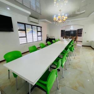 a conference room with a large white table and green chairs at Rosenia Boutique Hotel_Block 3 in Gaborone