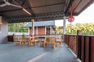 a patio with wooden tables and chairs on a deck at OYO 90149 Pua Family Semporna in Semporna