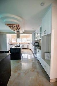 a large kitchen with white cabinets and a black island at Rosenia Boutique Hotel_Block 3 in Gaborone