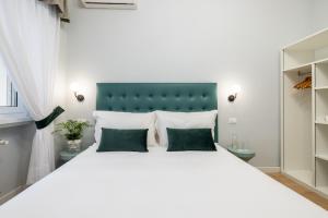 una camera da letto con un grande letto bianco con due cuscini verdi di Domus Bella Roma a Roma