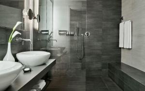 a black and white bathroom with a sink and a shower at Capovaticano Resort Thalasso Spa in Capo Vaticano