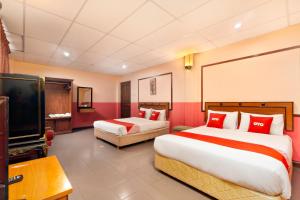 Habitación de hotel con 2 camas y TV de pantalla plana. en OYO 90929 DJ Hotel en Lumut