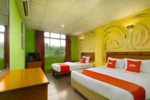 Habitación de hotel con 2 camas y TV en OYO 90929 DJ Hotel en Lumut