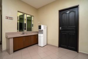 een badkamer met een wastafel en een koelkast naast een deur bij OYO 1194 Best Stay Hotel Pangkor in Pangkor