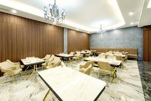 une salle à manger avec des tables, des chaises et des lustres dans l'établissement MirOtel, à Chimkent